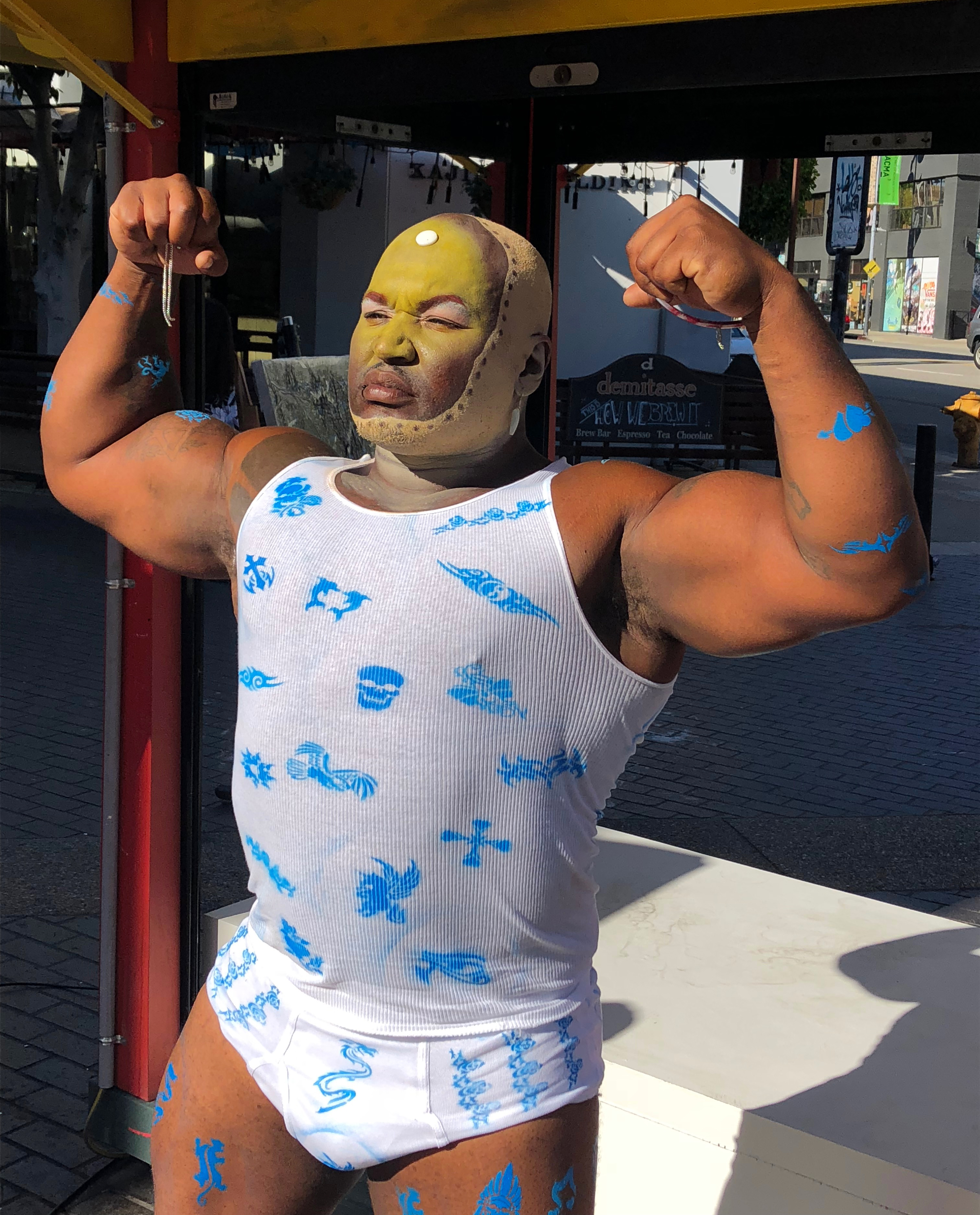 Detail A muscular black man in tank top and underwear flexing outside in the daylight